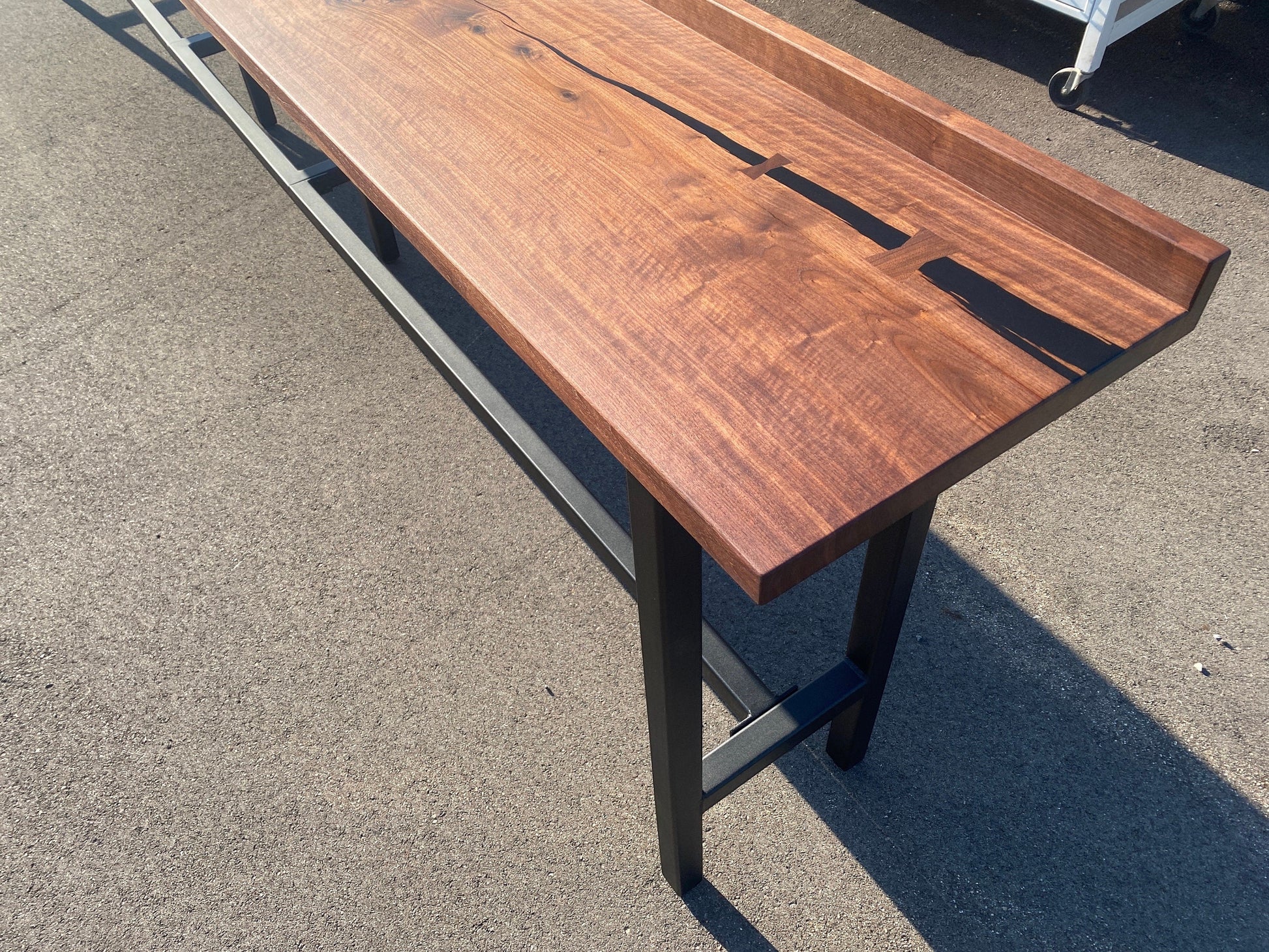 iReclaimed black walnut live edge bar table with dark steel legs and a natural finish. Features a drink rail and unique wood grain.